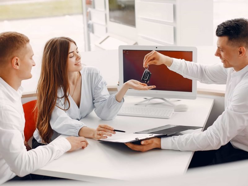 People buying a car. Beautiful woman in a white blouse. Manager working in a office.